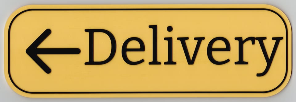 Direct scan of a Sunshine Yellow Delivery sign with matte black wording, border, left arrow, and rounded corners.