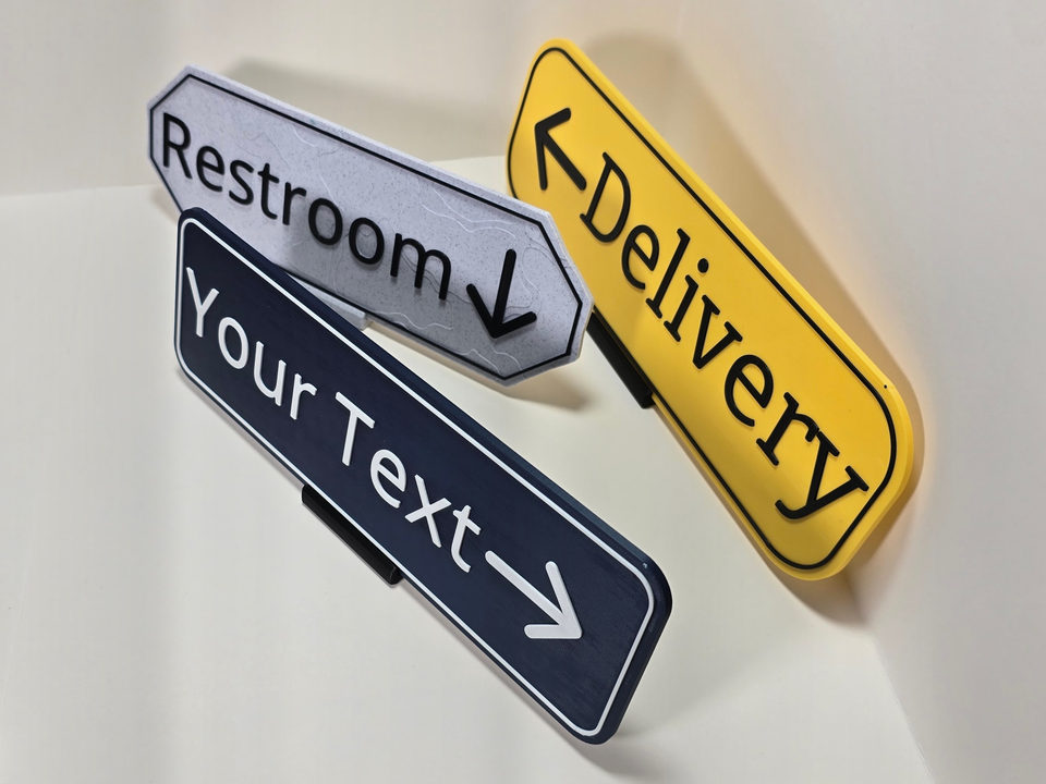 High angled view of three destination and arrow sign samples showing different shapes, finishes, and stands.