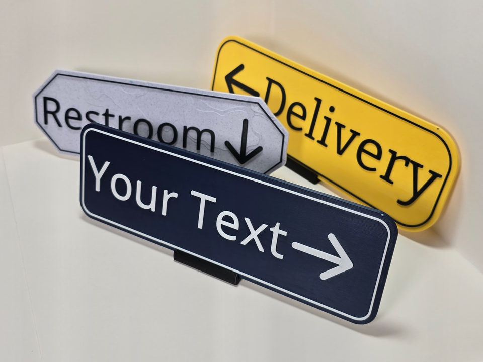 Angled perspective of three customizable destination signs in yellow, marble white, and navy blue.