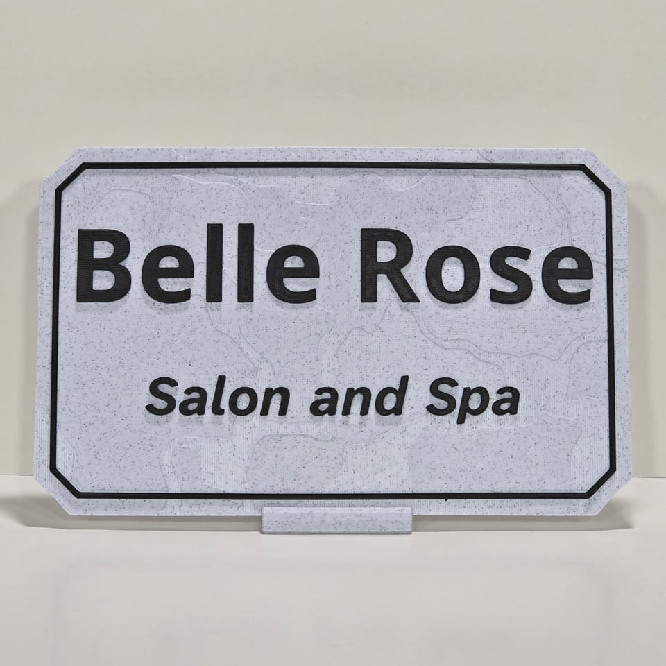 Marble-white business plaque reading Belle Rose and Salon and Spa on a matching tabletop stand.