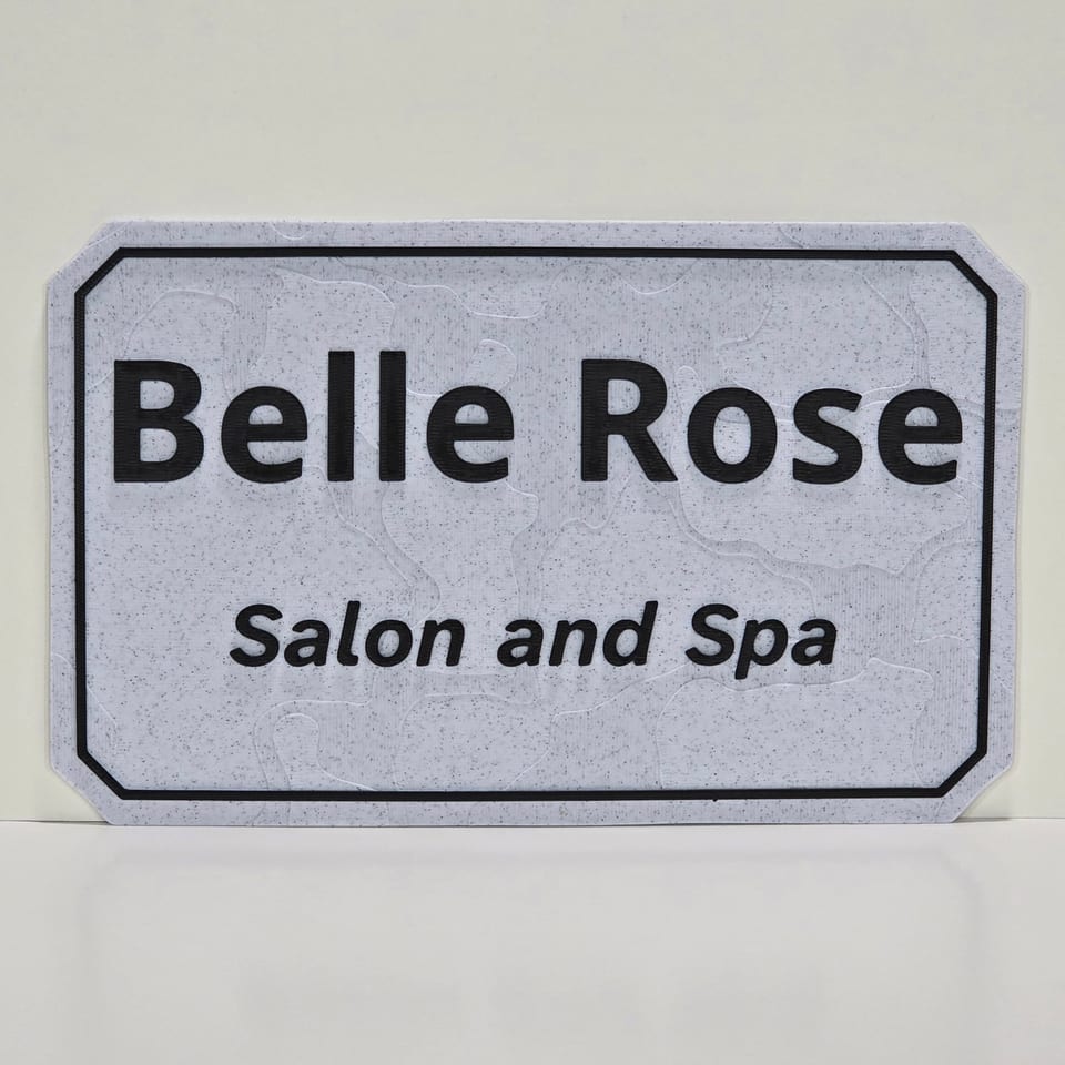 Straight-on marble-white business plaque reading Belle Rose and Salon and Spa with black lettering and border.