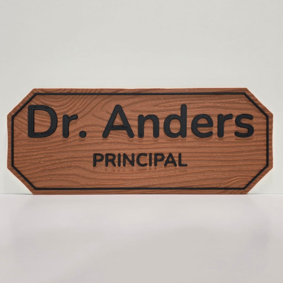 Straight-on wood-look staff nameplate reading Dr. Anders and Principal with black lettering and border.
