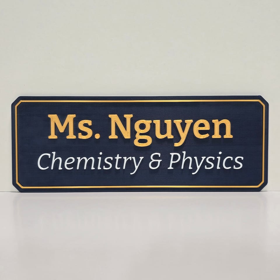 Straight-on navy teacher nameplate reading Ms. Nguyen and Chemistry & Physics with gold and white lettering and a gold border.