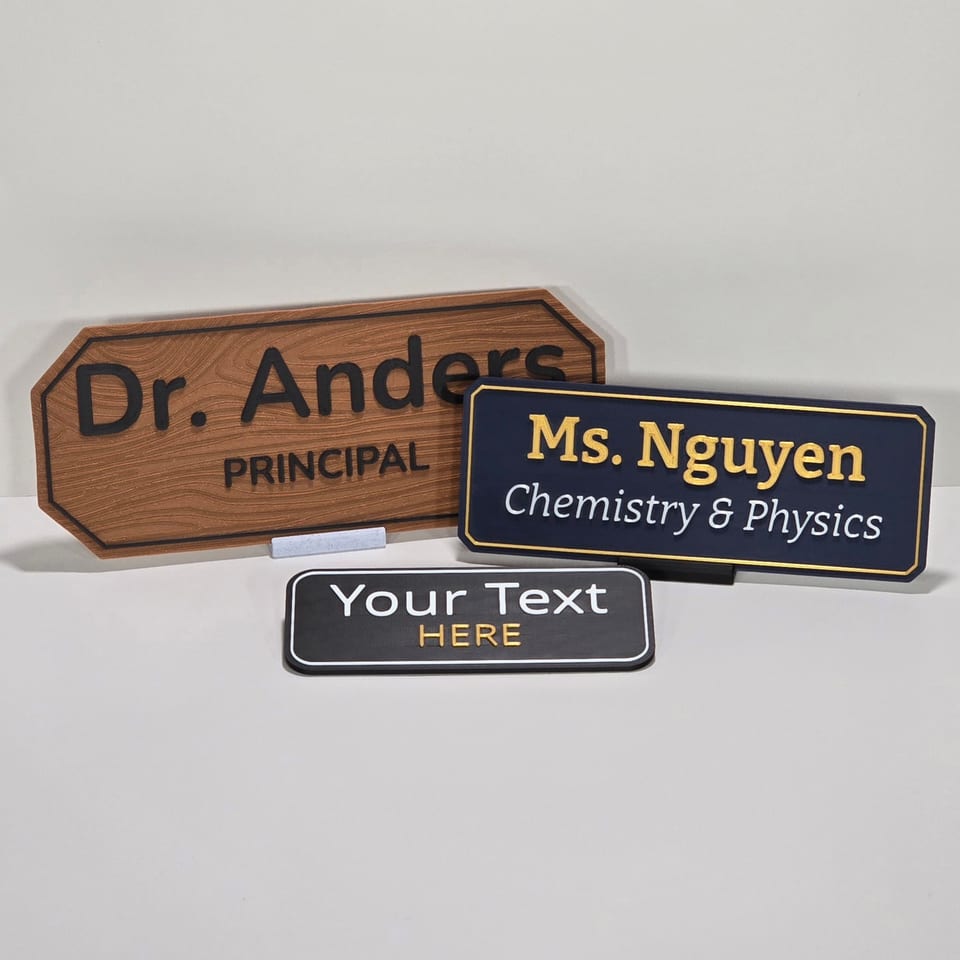 Front arrangement of three customizable teacher and staff nameplates in wood-look, navy, and black finishes.