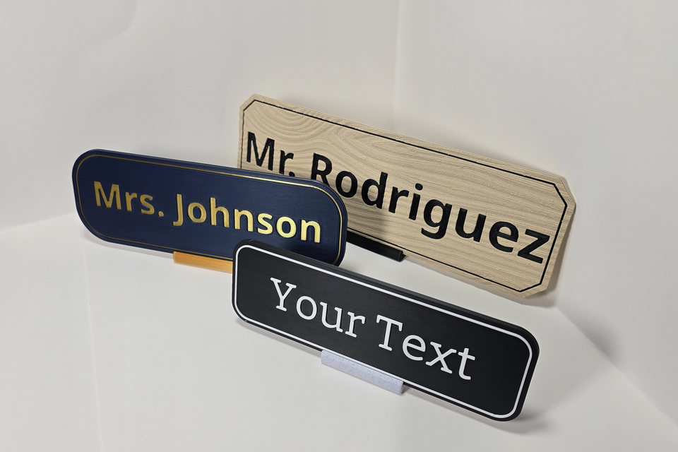 Angled view of three Teacher and Staff Nameplate samples showing their different sizes, finishes, edges, and tabletop stands.